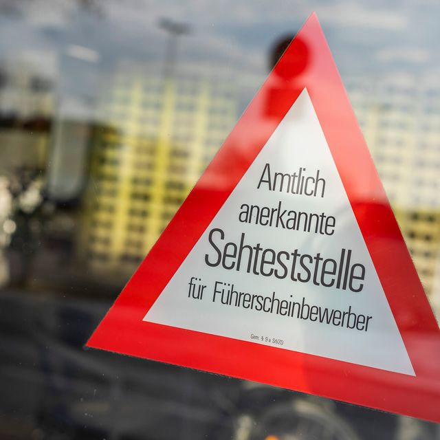 Dreieckiges Hinweisschild für Führerscheinsehtest im Schaufenster von Optiker Kugland in Plön